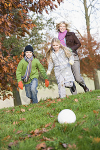 户外母亲与两名幼儿一起在公园里玩足球和微笑高清图片