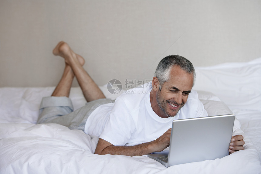在床铺上使用笔记本电脑的人技术设备沟通障碍访问用户硬件活动日常生活通讯图片