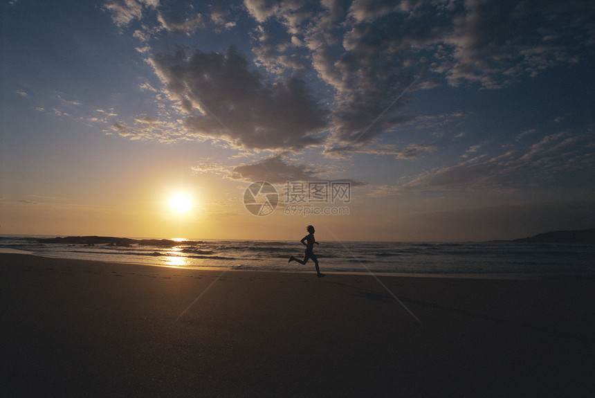 男子在日落时在海滩上户外奔跑(环影)图片