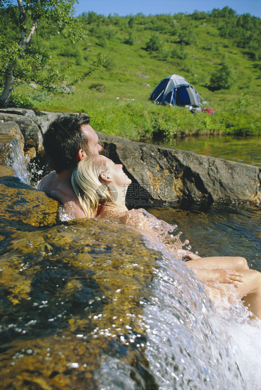 露营区户外的夫妇们在小溪中放松图片