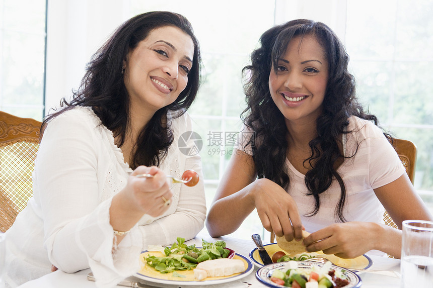 坐在晚餐桌边的两位妇女笑着高键情绪成年人餐厅女朋友女性女儿们情感美食朋友们友谊图片