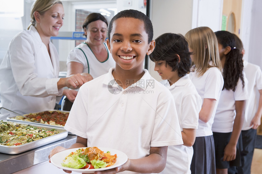 餐厅线上的学生 其中一人拿着健康饮食 看照相机深入田间工人饮食谷物成年人孩子服务员食堂男孩们美食围裙图片