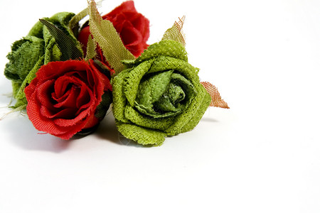 带有复制空间的红玫瑰和绿玫瑰宏观织物白色礼物花朵绿色背景图片