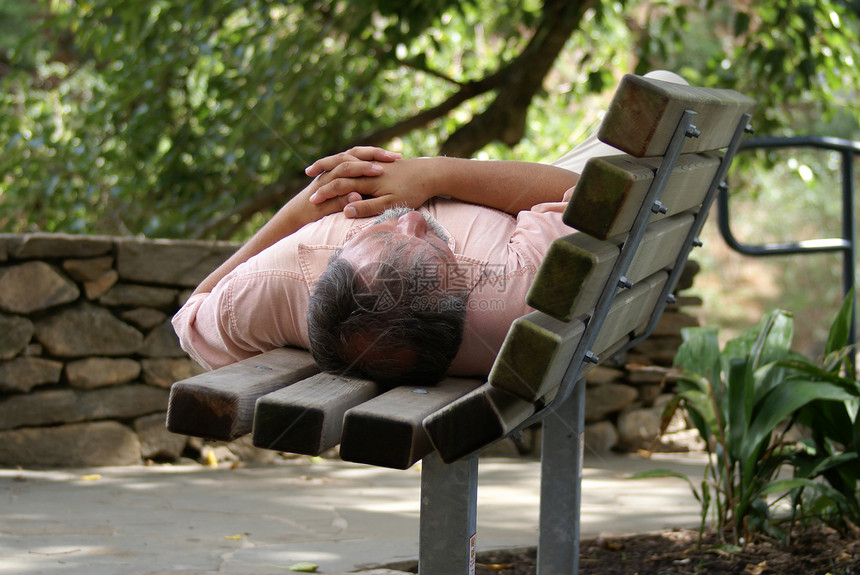 无家可归的人睡在公园长椅上图片