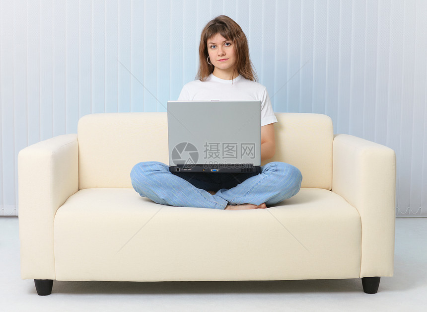 美人用笔记本电脑坐在沙发上褐色蓝色家具长沙发白色女士女性女孩图片
