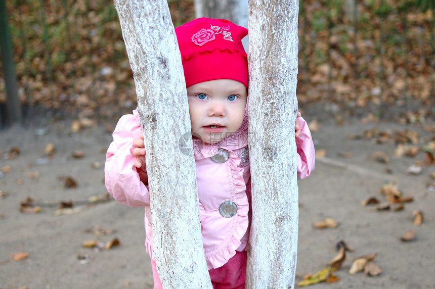 漂亮的小女孩留在树后面婴儿森林孩子公园木头金属女孩停留水晶裤子图片