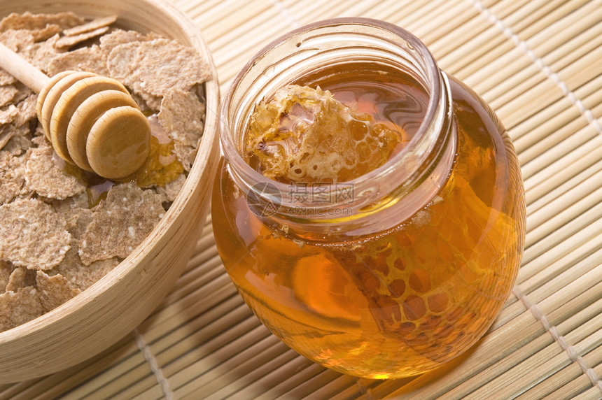 带蜂窝和早餐薄片的新鲜蜂蜜勺子甜点水果玻璃饮食宏观盘子花蜜玉米糖浆图片