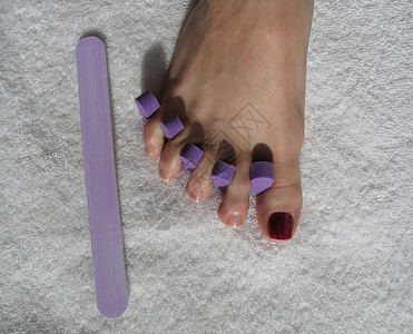 修脚期间的女足女性化指甲油指甲抛光毛巾脚趾水平化妆品背景图片
