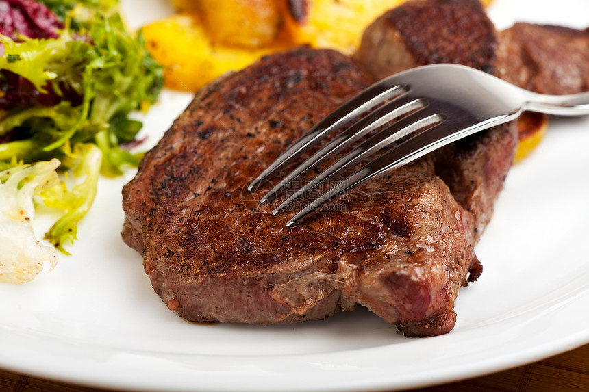牛排上的银叉加沙拉和土豆肉汁用具牛肉蔬菜午餐门房棕色红色食物宏观图片