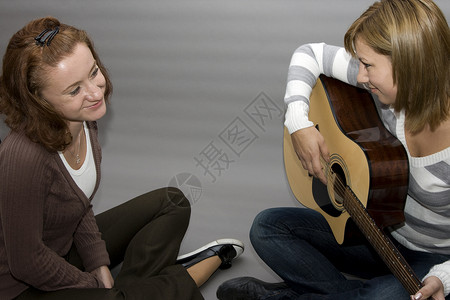 弹吉他吉他牛仔裤楷模音乐女士女性吉他手黑发女孩们工作室背景图片