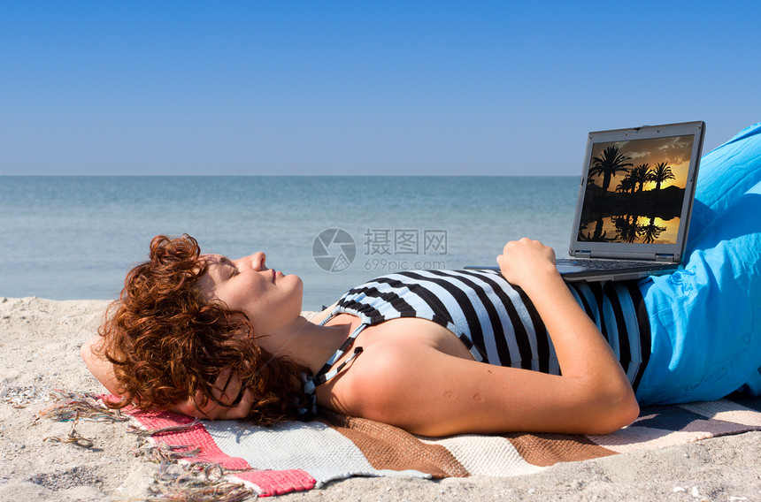 睡在海上海岸的膝上型电脑的妇女图片