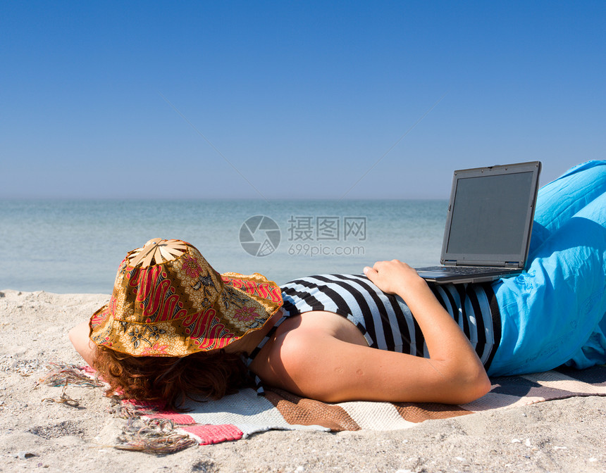 女孩睡在海滨的膝上型电脑图片