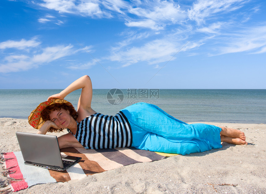 海边携带膝上型电脑的妇女图片