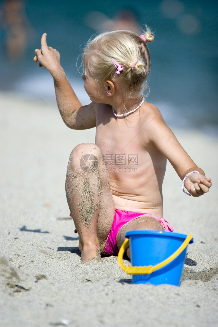海滩上的女孩晴天海洋天空头发乐趣蓝色童年微笑孩子玩具图片