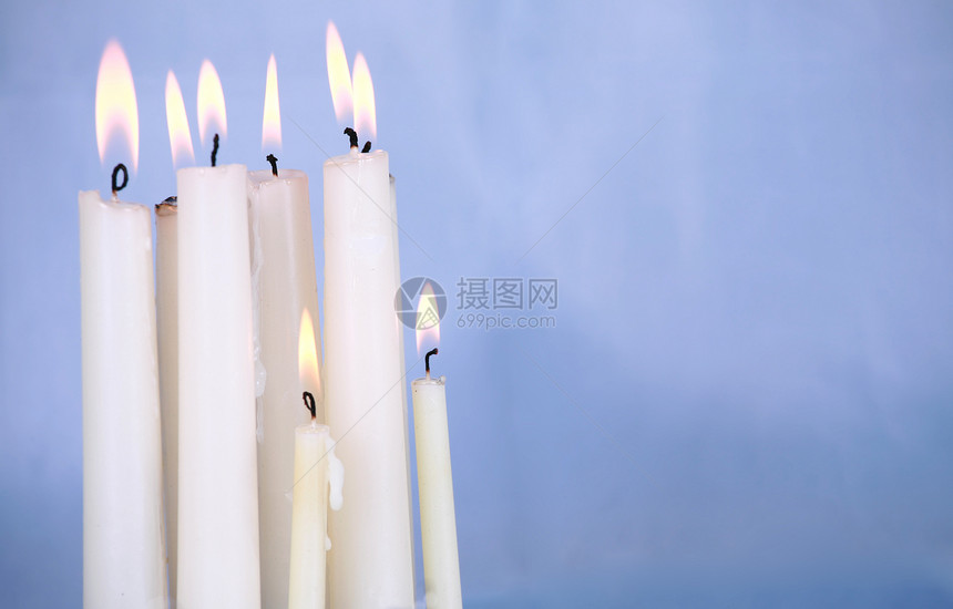 在蓝色背景下燃烧的蜡烛图片