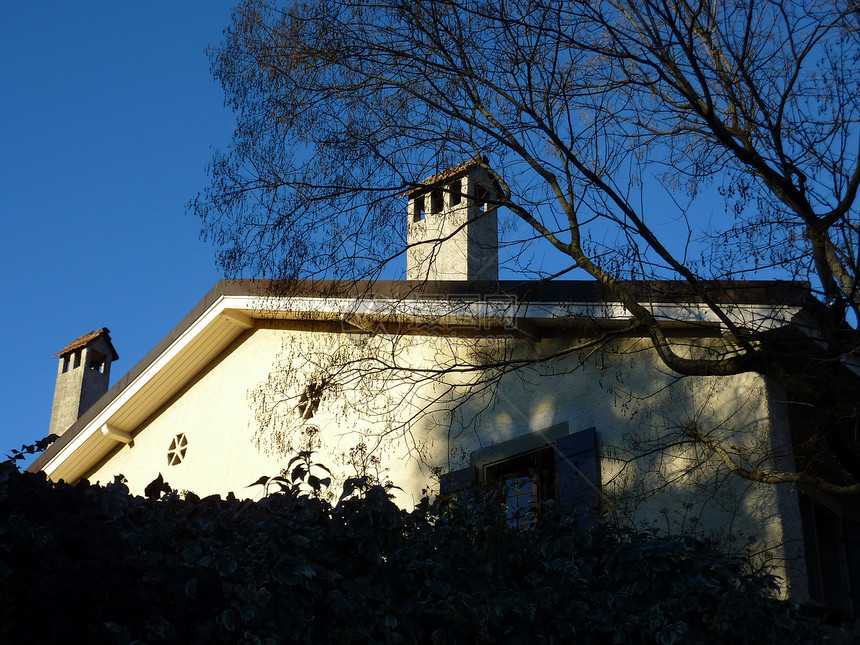 房子的屋顶烟囱窗户天空树篱阴影晴天住宅蓝色图片