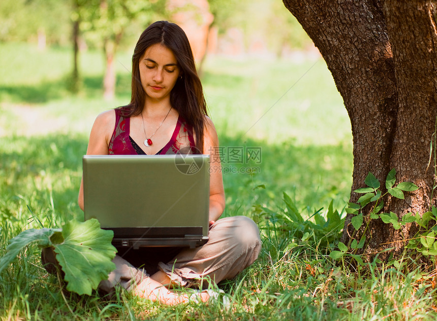 快乐的年轻女人在户外用笔记本电脑幸福时候阳光衣服技术通讯活动成人女性假期图片
