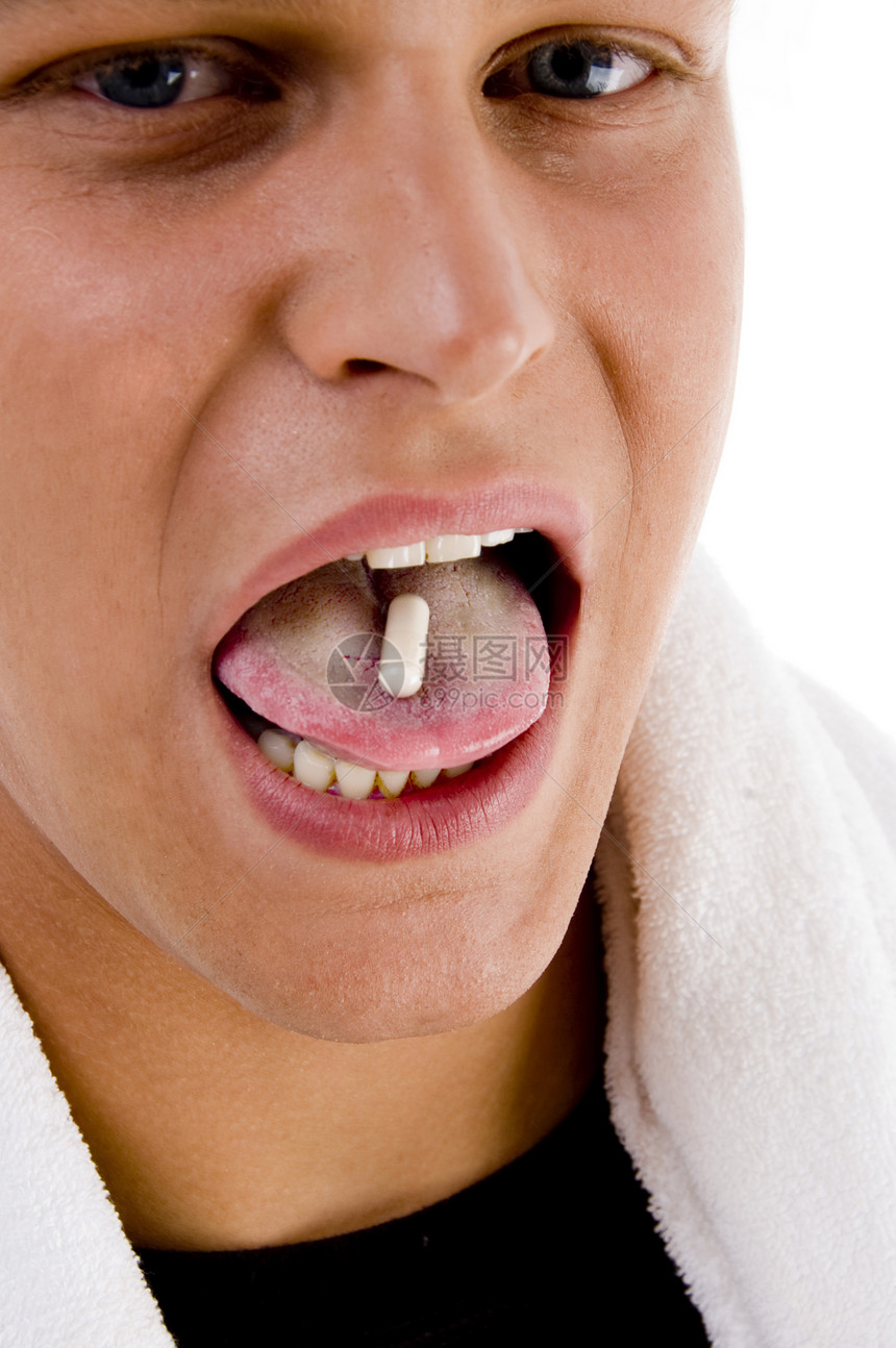 青年男子用药丸在他的舌头上图片