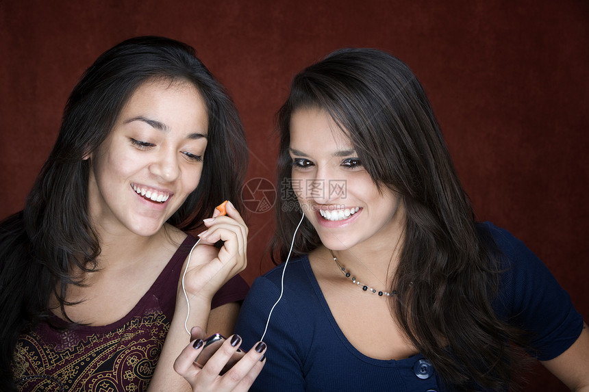 两名青年女听音乐的妇女微笑快乐电子金属播客音乐姐姐女士水平耳机图片