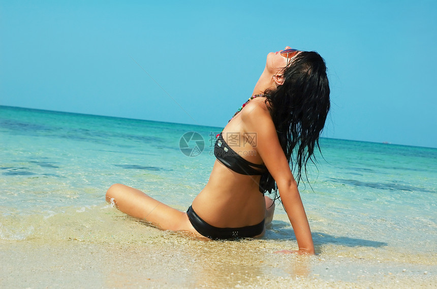 海滩上美丽的女人海岸棕褐色游客游泳衣拥抱头发蓝色假期海洋旅行图片