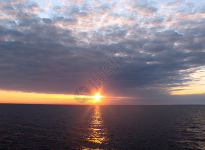 傍晚的海上蓝色日落黄色雨云光束橙子红色太阳反射背景图片