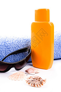 毛巾 贝壳 太阳镜和润滑剂奶油海洋太阳洗剂黄色化妆品蓝色白色丁字裤棕色背景图片