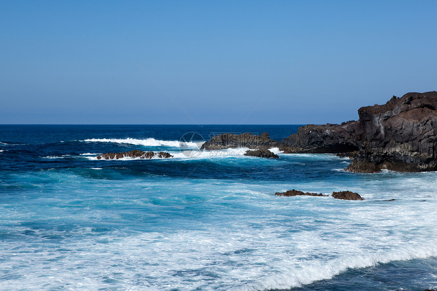 海滨熔岩海浪海岸泡沫海洋表面日光岩石蓝色天空图片