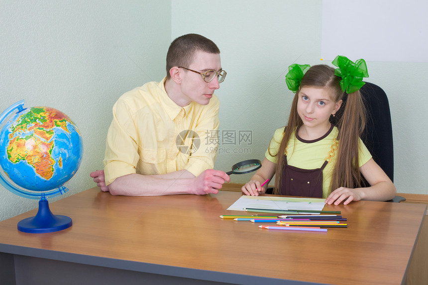 带彩色铅笔的女孩和兄弟放大镜孩子女学生绘画写字桌叶子地球男性桌子姐姐图片