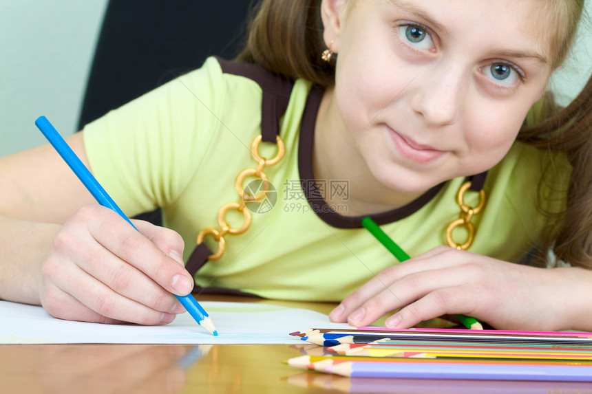女孩拿着蓝铅笔棕色写字桌画家绘画女学生绿色水平微笑蜡笔相似度图片