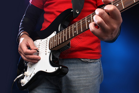 玩电吉他乐器红色细绳黑色指板男性音乐家岩石音乐牛仔裤背景图片