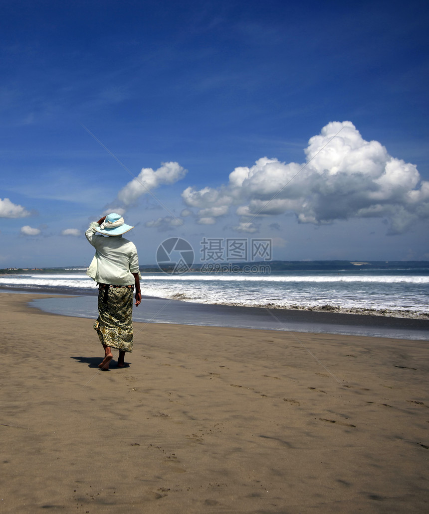 海滩上的女人蓝色孤独海岸线海岸旅行成人石头天空裙子女士图片