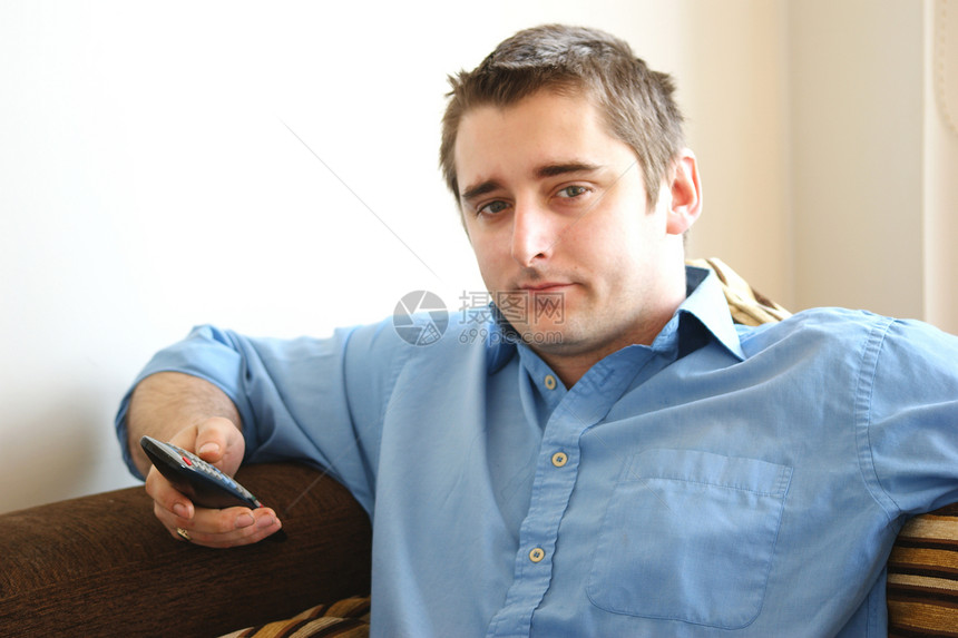 男人在家做男人蓝色衬衫沙发房子电视闲暇长椅白色图片