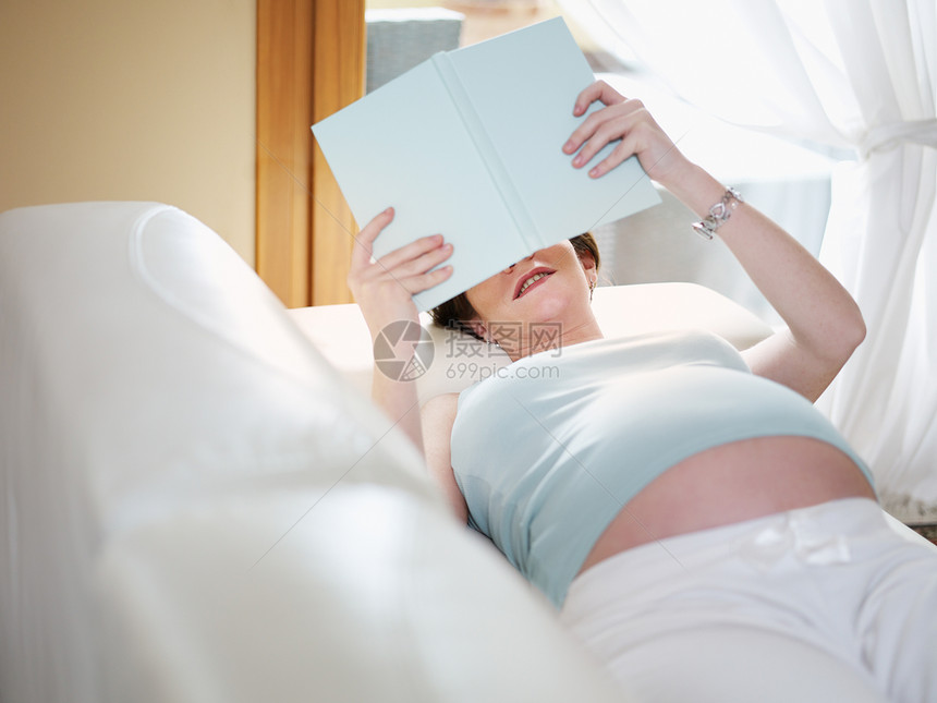 家庭阅读书本的孕妇母亲女性享受中年人腹部成人背心快乐父母母性图片