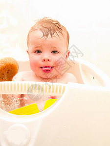 快乐的男孩在洗澡时坐在浴缸里背景图片