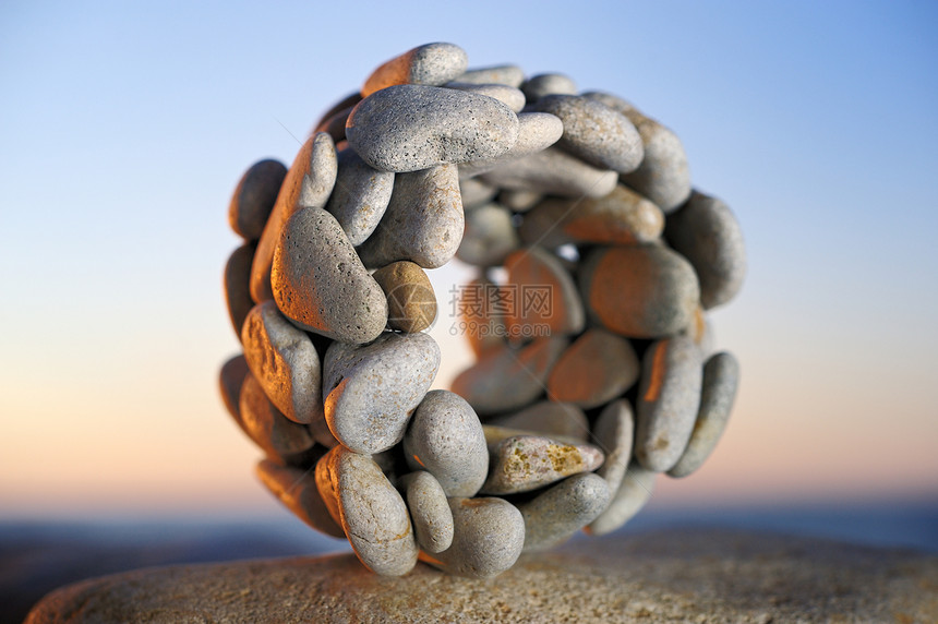 环绕日落灰色石头岩石海滩卵石图片
