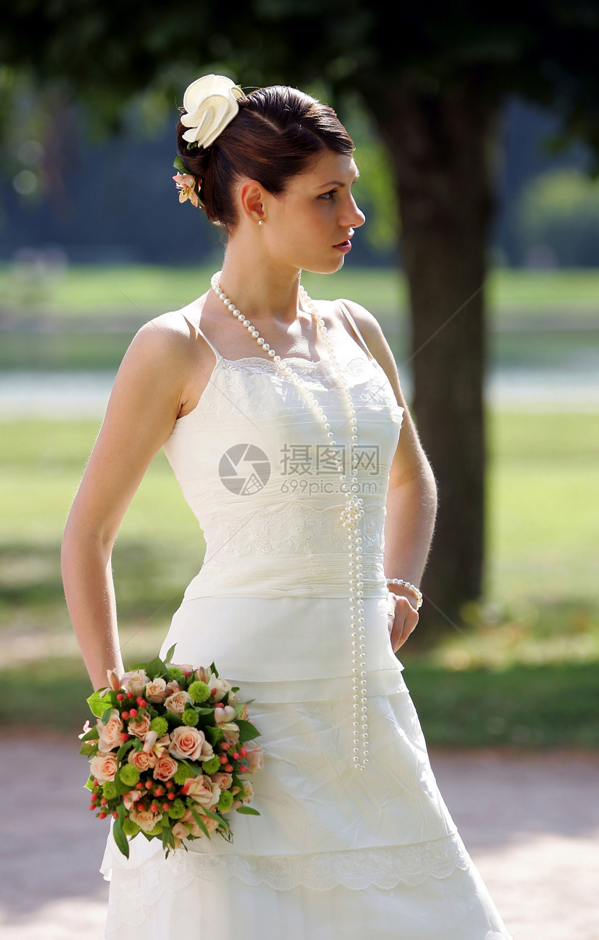 年轻新娘拿着花束冒充服装花朵新人思维姿势黑发女性白色裙子图片