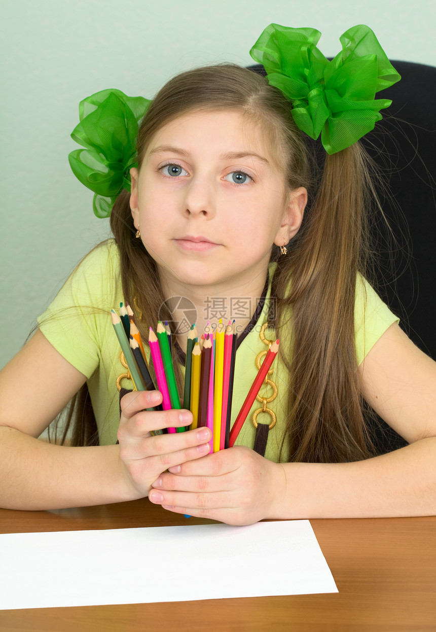 手拿着彩色铅笔的女孩绿色桌子女学生写字桌照片叶子娘娘腔黄色画家孩子图片
