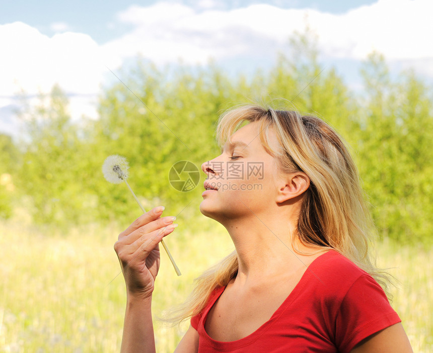 女孩吹在花朵上乐趣幸福金发女郎生活自由植物嘴唇微笑头发享受图片