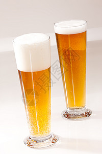 冷啤酒黄色玻璃状高脚杯玻璃饮料泡沫背景图片