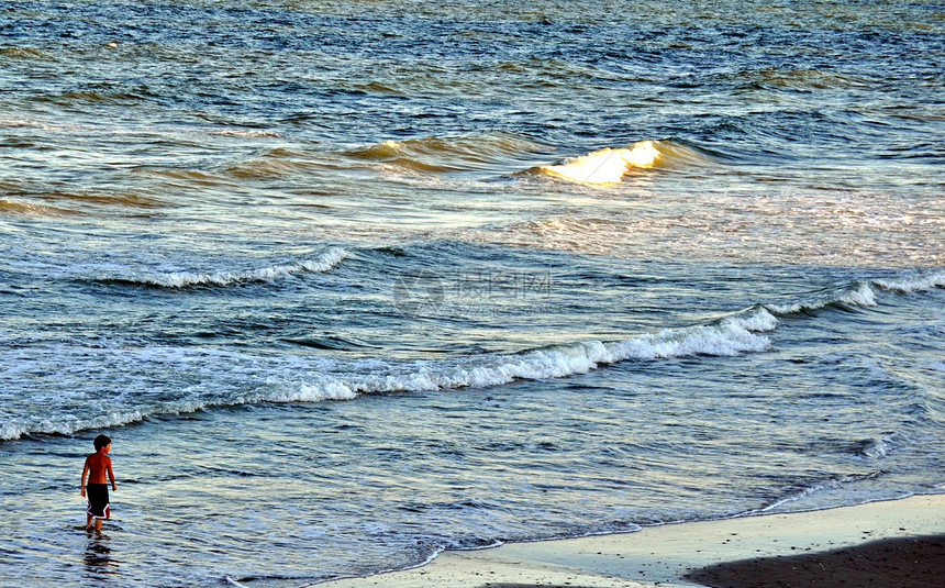 男孩在波浪中漫步海洋蓝色海浪儿子男生海滩男性贝壳推介会天空图片