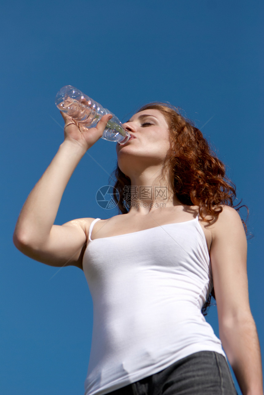 女孩从瓶子对天的饮水中喝水图片