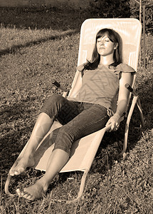 年轻女性放松椅子成人睡眠贷款太阳女孩享受阳光院子休息背景图片