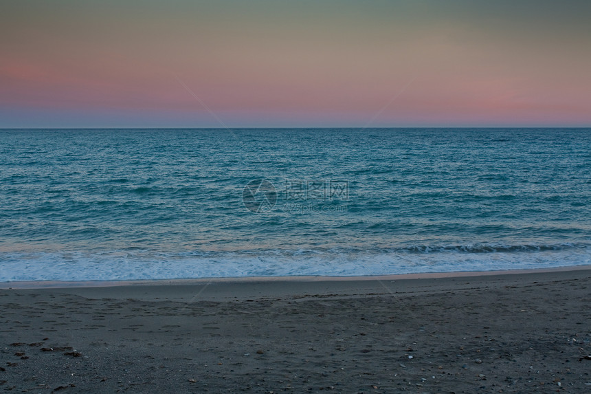 黄昏时的海景冲浪全景海洋黄色蓝色支撑阴霾波浪鹅卵石海岸图片
