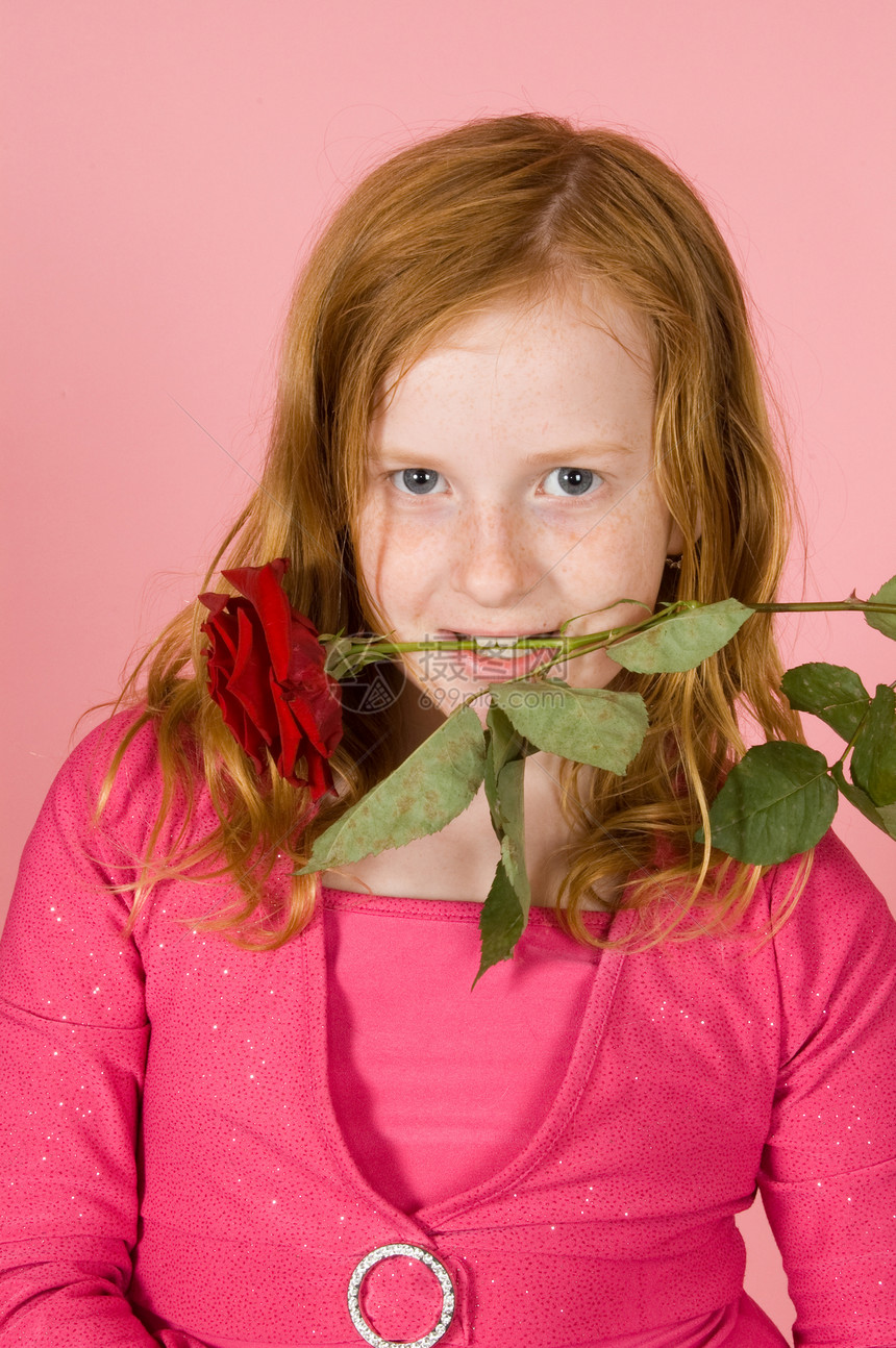 年轻女孩的牙齿间夹着红玫瑰图片