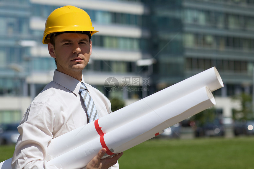 硬帽建筑师在建筑工地持有蓝图的肖像图图片