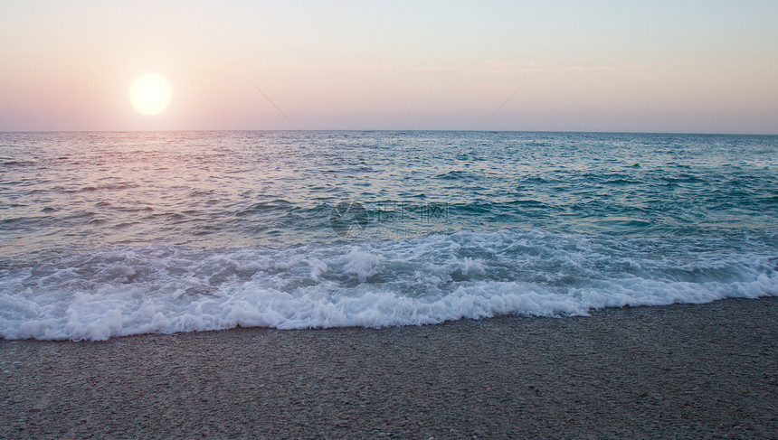 海中的日落天际太阳地平线风景波浪反射天空紫色黑色海岸线图片