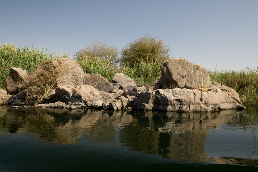 埃及阿斯旺附近尼罗河帆船蓝色反射阳光旅行风景假期河岸岩石石头图片