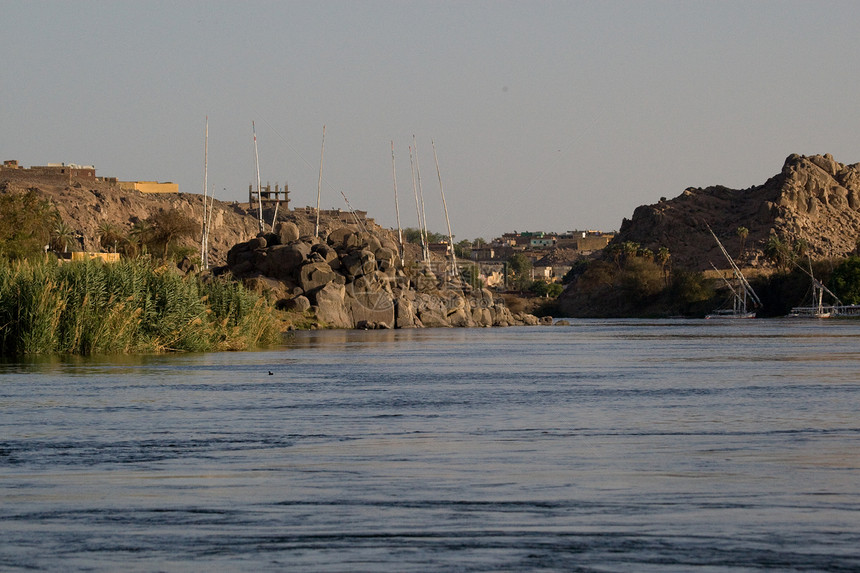 埃及阿斯旺附近尼罗河蓝色航海假期旅游岩石沙漠晴天反射阳光河岸图片