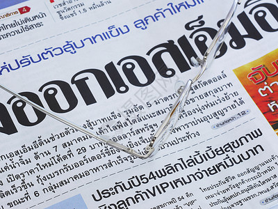 泰语报纸和一副眼镜的贴合版背景图片
