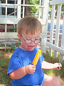 吃棒冰的男孩得了唐氏综合症的男孩 吃冰棒青年橙子蓝色食物生活小吃男性孩子乐趣男生背景